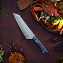 The Messermeister Iron & Resin Overland Chef 8″ Camp Knife rests on a dark surface beside a plate of cooked crab, lemon slices, fresh herbs, scissors, and a small bowl of stew scattered with spices and greens—an ideal choice for outdoor cooking adventures.