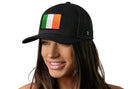 A woman smiles against a white background, wearing the Haka Hat Ireland Flag Trucker Hat by Haka Hat—a black Irish snapback featuring their signature trucker design and an embroidered Irish flag patch on the front.