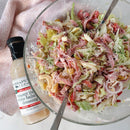 A glass bowl of chopped salad sits beside a bottle of Terrapin Ridge Farms Terrapin Ridge Creamy Italian White Balsamic Dressing, with a spoon and fork ready to enjoy this flavorful salad accompaniment.