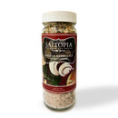 A clear plastic jar of SALTOPIA Infused Sea Salts, labeled "Saltopia Italian Herbs & Garlic Salt: KITCHEN'S KEEPER," features images of mushrooms, herbs, and food. It blends Italian herbs and salt for flavorful everyday seasoning.