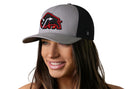 A smiling woman wears the Haka Hat JBR x Haka Red Bison Gray-Black Buffalo Snapback, featuring a red and black bison logo on the front. Brand: Haka Hat. The background is white.