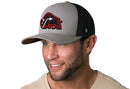 A man wears the Haka Hat JBR x Haka Red Bison Gray-Black Buffalo Snapback, a trucker hat by Haka Hat featuring bold red and black buffalo embroidery with a white arrow and a black mesh back.