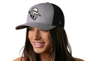 A woman with long brown hair smiles while wearing a Haka Hat JBR Silver Logo Gray Black Metallic Leather Snapback by Haka Hat. The background is plain white.