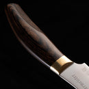 Close-up of the Messermeister Kawashima Paring Knife - 3.5" featuring a polished wooden handle, metal bolster, and a partial view of the SG2 powdered steel blade by Messermeister, set against a black background.