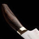 Close-up of the Messermeister Kawashima 6" Utility Knife, showcasing its polished dark wood handle, brass bolster, and engraved stainless steel blade—an essential kitchen tool—set against a black background.