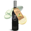 A bottle of Georgetown Olive Oil Co. Lemon Cucumber White Balsamic, from Georgetown Olive Oil Co., crafted with aged white balsamic vinegar from Modena, Italy, is displayed with a tag in front of sliced cucumber and half a lemon.