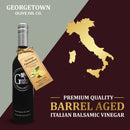 A bottle of Georgetown Olive Oil Co. Lemon Cucumber White Balsamic, crafted in Modena, Italy, is displayed beside a gold map of Italy on a maroon and cream backdrop with premium quality messaging. This distinctive white balsamic vinegar features lemon and cucumber flavors, showcasing the rich tradition and exceptional taste linked to its genuine Italian heritage.