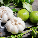 Two whole garlic bulbs and two green limes rest on rustic wood, ready to inspire your own Lime Garlic Salt—or enjoy SALTOPIA Infused Sea Salts' Lime Garlic Salt to elevate any dish with vibrant flavor.