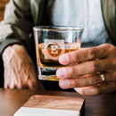 A person holds a Whiskey Glasses: Medalist, featuring the letter E engraved in a decorative square border.