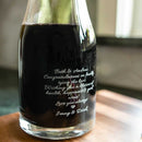 A Wine Decanter - The Medalist filled with red wine, featuring a personalized engraving with a wedding congratulatory message for Beth and Andrew from Jenny and Derek, making for a unique custom wine gift.