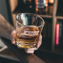 A person holds a Whiskey Essentials Bundle whiskey glass personalized with an engraved label reading ALLEN.