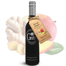 A bottle of Georgetown Olive Oil Co Mango Ginger White Balsamic Vinegar, featuring a tag and the Georgetown Olive Oil Co. logo with a Washington, DC address, is displayed in front of fresh ginger root and a mango. This unique white balsamic vinegar is crafted from aged white balsamic vinegar traditionally sourced from Modena, Italy.