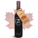 A bottle of Georgetown Olive Oil Co Maple Infused Balsamic Vinegar from Georgetown Olive Oil Co., complete with a maple leaf tag, is displayed in front of a large, faded maple leaf background.