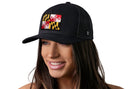 A woman with long brown hair smiles while wearing a Haka Hat Maryland Flag Trucker Hat | Black MD Snapback by Haka Hat, featuring a Maryland state flag patch on the front. The background is plain white.
