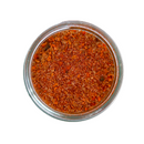 A glass jar of SALTOPIA Infused Sea Salts' BBQ Salt: MEAT HEAD, a coarse, reddish-orange Texas BBQ seasoning blend, viewed from above against a white background.
