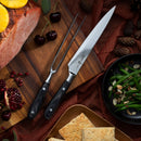 The Messermeister Avanta Damascus Carving Set - 2 Piece sits on a wooden board with sliced meat, cherries, pomegranate, green beans with almonds, and crackers atop a brown cloth.