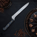A Messermeister Custom Scalloped Offset Knife - 8" with a black handle lies on a dark surface beside a glossy chocolate cake topped with swirls, curls, and chocolate shavings.