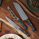 Three Messermeister kitchen knives, including the Custom Utility Knife - 6" with black handle, are arranged on a wooden cutting board. Nuts, cinnamon sticks, and part of a pie surround the board.