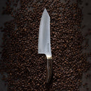 The Messermeister Kawashima Magnet Block Set - 5 Piece by Messermeister rests on a dark surface, its elegant blades and wooden handles beautifully displayed among scattered coffee beans.