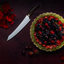 A fruit tart with berries sits on a dark surface next to the Messermeister Kawashima Magnet Block Set - 5 Piece, featuring premium knives, red rose petals, and loose cherries and strawberries.