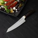 The Messermeister Kawashima Magnet Block Set - 5 Piece by Messermeister, featuring SG2 steel blades and dark wooden handles, is displayed on a black textured surface beside a salad with greens, tomatoes, goat cheese, and smoked salmon.