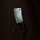 The Messermeister Pro Series Heavy Meat Cleaver - 6", made of high-carbon stainless steel with a black handle, rests on a dark wooden surface.