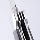 Close-up of the Messermeister Adventure Chef Linen Folding Camp Utensil, partially open to reveal its metal blade, liners, and spacers against a plain white background.