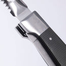 Close-up of the Messermeister Adventure Chef Linen Folding Peeler & Parer, featuring a textured dark handle and a partially opened stainless steel blade, set against a plain white background.