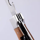 Close-up of the Messermeister Adventure Chef Maple Folding Camp Utensil, featuring a wooden handle and partially unfolded fork and bottle opener, ideal for outdoor cooking adventures.
