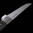 A close-up of the Messermeister Adventure Chef Linen Folding Flexible Fillet Knife - 6" shows its partially open stainless steel blade engraved with “NESSMUKFISH” and a green textured handle, set against a black background.
