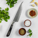 The Messermeister Avanta Damascus Starter Set - 3 Piece, crafted by Messermeister, rests on a white surface amid fresh cilantro, garlic cloves, a bowl of crushed red pepper, salt, ground pepper, and a parsley leaf.