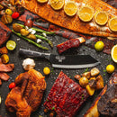 The Messermeister Avanta Kendrick BBQ Knife - 8", crafted from German X50 stainless steel, is surrounded by grilled salmon with lemon, ribs, roast chicken, potatoes, green beans, tomatoes, and garlic on a dark rustic surface.