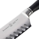 Close-up of the Messermeister Blacksmith Kullens Santoku Knife - 6.5" with a black handle, German stainless steel blade, and hollow edge grooves, featuring the Messermeister brand name and Solingen, Germany engraved on the blade.
