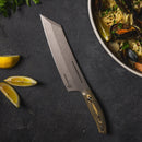 A Messermeister Carbon Bunka Chef's Knife - 8" with a wooden handle rests on a dark countertop beside lemon wedges and a large bowl of pasta with mussels and herbs.