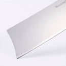 Close-up of the blade of a Messermeister Custom Red Nakiri Knife - 6.5" on a white background, highlighting its sharp edge and smooth, reflective surface with part of the Messermeister brand name visible on the blade.