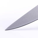 Close-up of the sharp pointed tip of the Messermeister Custom Red Utility Knife - 6", featuring a red handle, set against a plain white background—ideal for precise kitchen prep.