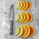 A Messermeister Custom Utility Knife - 6" by Messermeister rests on a gray surface next to three rows of citrus—lime, lemon, and orange—each row showcasing four wedges in size order from smallest to largest.