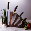 The Messermeister Kawashima Magnet Block Set - 5 Piece by Messermeister features SG2 steel kitchen knives with wooden handles, beautifully displayed in a magnetic wood block on a marble counter amid fresh herbs, garlic, asparagus, and radishes.