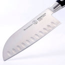 A close-up of the Messermeister Meridian Elite Kullens Santoku Knife - 7" shows oval indentations on the German-forged steel blade and part of its black handle.
