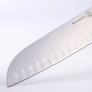 Close-up of a Messermeister Meridian Elite Kullens Santoku Knife - 5" blade made from high-carbon stainless steel, with oval-shaped indentations and the Messermeister logo engraved, set against a plain white background.
