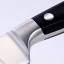 Close-up of the Messermeister Meridian Elite Kullens Slicer - 10", showing part of the German-forged blade, bolster, and black riveted handle against a light background.