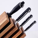 The Messermeister Meridian Elite Next Level 5-Piece Block Set features German stainless steel knives with black handles and a sharpener, all stored in an angled wooden block.