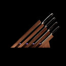 A set of five kitchen knives with metallic handles is displayed in a Messermeister Next Level Magnetic Knife Block - UV Light, positioned diagonally against a black background.