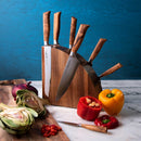 The Messermeister Knife Gallery Magnetic Knife Block for Countertop Storage by Messermeister serves as a sleek and modern organizer on a marble countertop, securely holding five knives. Neatly arranged beside it are sliced vegetables—including artichoke, red onion, yellow and red bell peppers—along with a vibrant red chopping board knife. This elegant kitchen scene is set against a calming blue wall background.