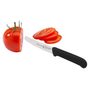 The Messermeister Black Serrated Tomato Knife with Matching Sheath (4.5") is slicing a ripe red tomato; one half remains uncut and several slices are arranged beside it.