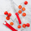 A Messermeister Red Serrated Tomato Knife with Matching Sheath (4.5") rests on white marble, surrounded by whole and halved cherry tomatoes.