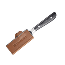 A kitchen knife with a black handle lies on a white background, its blade secured by the Messermeister Saddle Brown Leather Magnetic Edge-Guard - 4", embossed with the Messermeister brand name.