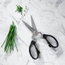 Messermeister Black Take-Apart Kitchen Scissors - 8" rest on a marble surface beside fresh chives and a small pile of chopped chives.