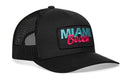 The Haka Hat Miami Beach Trucker Hat by Haka Hat is a black snapback with mesh back, curved brim, and a front patch embroidered "MIAMI Beach" in blue and pink letters.