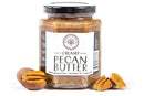 A jar of Millican Pecan Creamy Pecan Butter - 8.5 oz Natural Texas Pecan Spread sits with three Texas pecans—two shelled, one unshelled—on a white background.